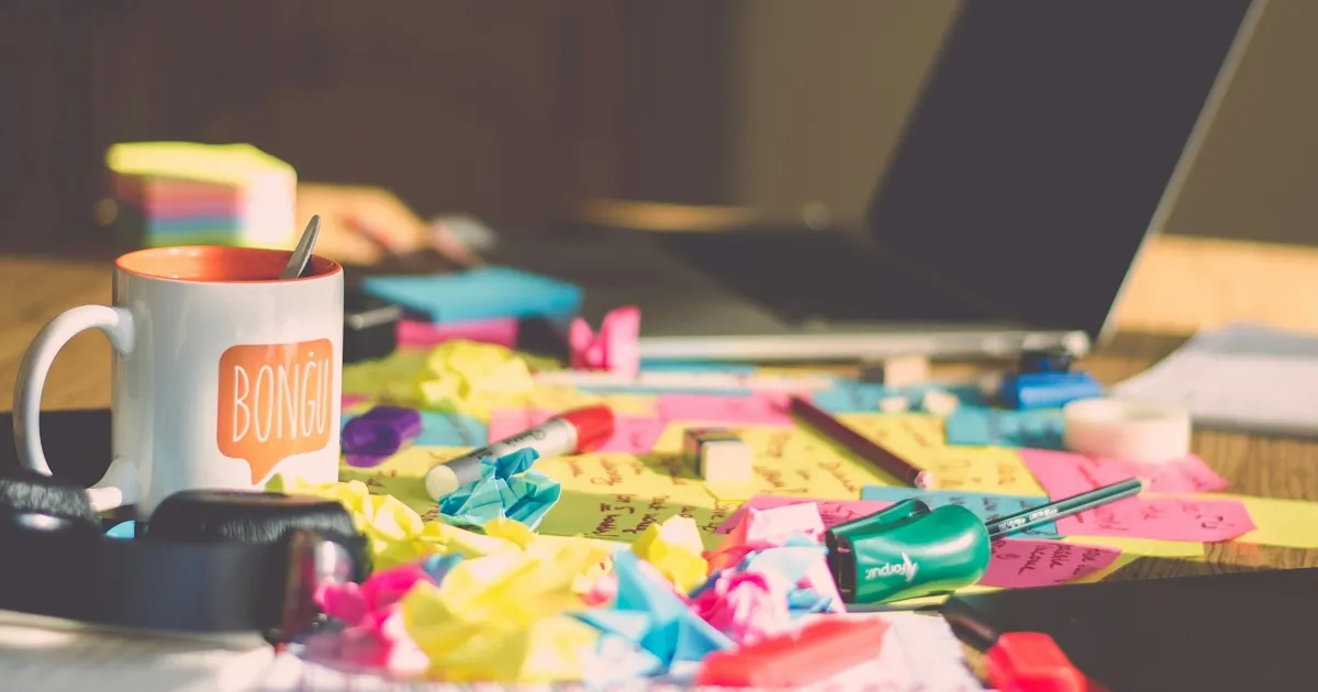 A messy, unkempt desk full of sticky notes, some crumpled up.